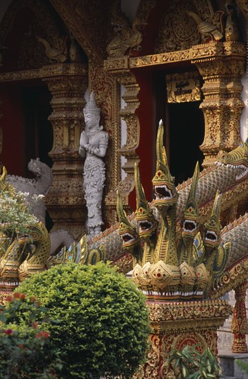THAILAND, North, Chiang Mai, Wat Bupparam Temple on Tha Phae Road. Temple exterior with elaborate dragon stairway banisters and statue near doorway.