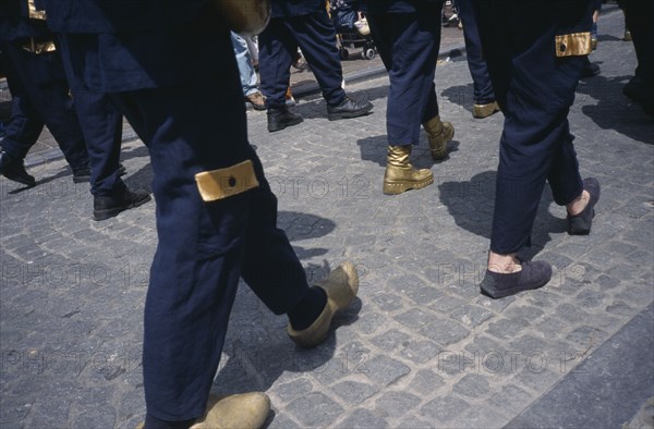 BELGIUM, West Flanders, Bruges, Parade of people wearing golden Clogs in Steenstraat during Braderie festival