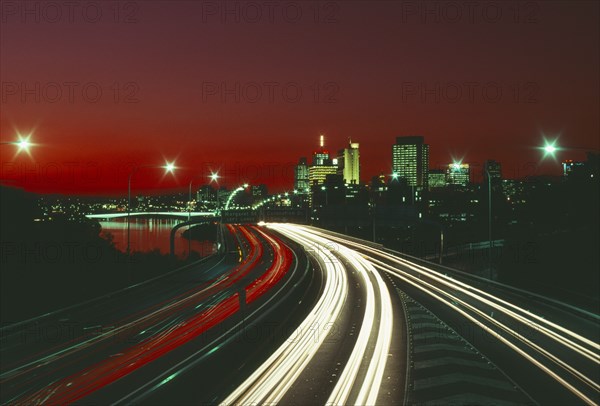 AUSTRALIA, Queensland, Brisbane, The south east freeway approaching the city illuminated at night with red and white traffic light trails.