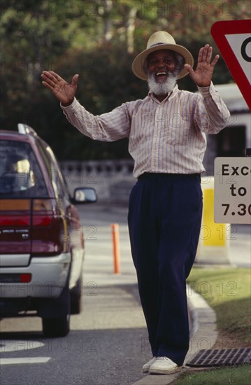 BERMUDA, Hamilton, Local character Johnny Barnes at roadside laughing and throwing his hands up in the air.