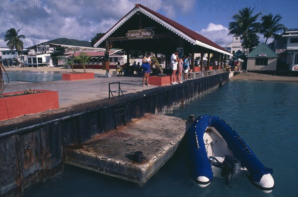 WEST INDIES, Dutch Antilles, St Maarten, Philipsburg.  Quayside with tourists looking in the water and the Captain Hodge Wharf behind.  Dingy moored in the foreground.