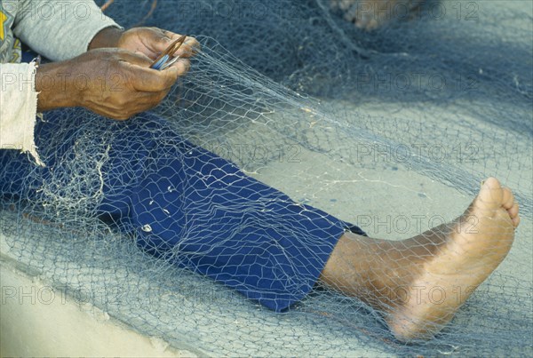 WEST INDIES, St Lucia, Anse La Raye, "Fishermen repairing nets on the beach, view of bare feet, hands and nets."