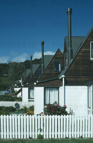 NEW ZEALAND, South Island, Akaroa, Line of houses with narrow chimneys and white painted picket fences.