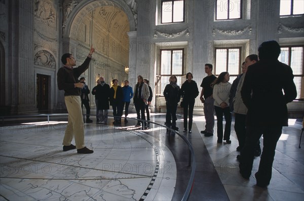 HOLLAND, Noord Holland, Amsterdam, "Visitors in the Citizens Hall of the Royal Palace, with tour guide standing on a map of the Old World tiled on the floor."