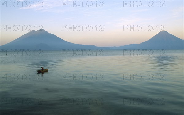 GUATEMALA, Panajachel, Lake Atitlan, View of a boat sailing on the lake with two Volcanoe peaks in the distance.
