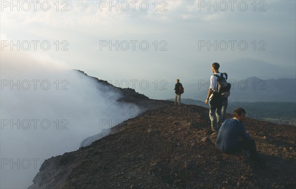 GUATEMALA, Pacaya Volcano, People standing on the rim of the smoking crater.