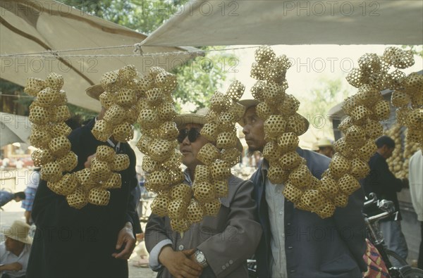 CHINA, Linxia, Buyers looking at  Woven bamboo cricket cages strung together and hung up on a stall.