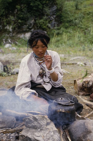 CHINA, Tibet, Tibetan woman boiling tea on the roadside.