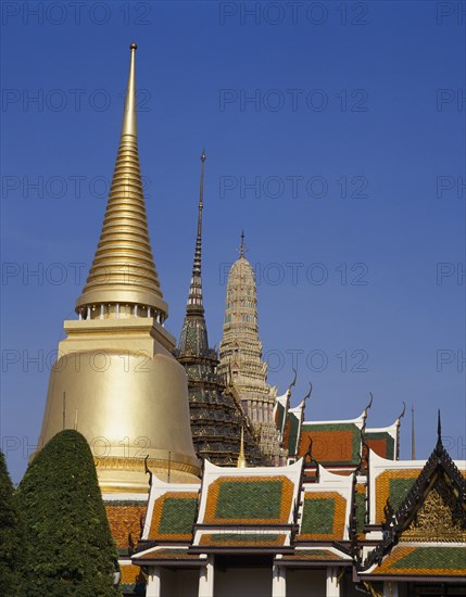 THAILAND, Bangkok, Wat Phra Kaew, Aka the Grand Palace. Colourful rooftops and spires with golden spire in the foreground.