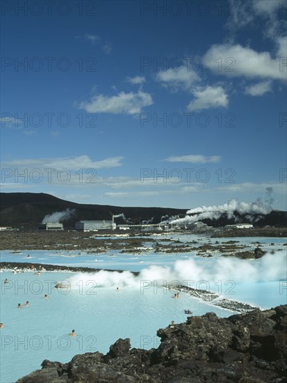 ICELAND, Near Grindavik, Blue Lagoon, View over steaming waters with bathers toward Svartsengi power station.