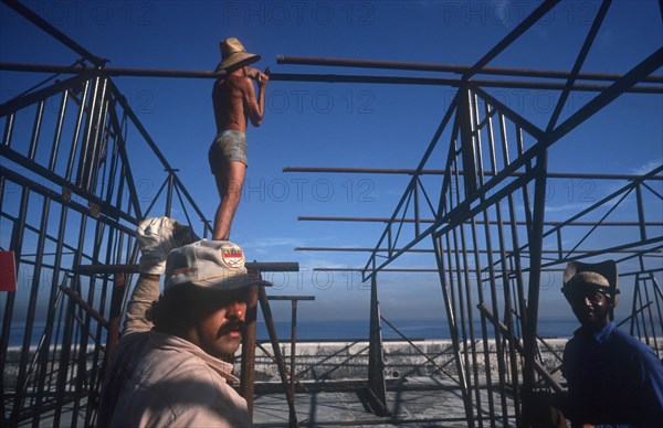 CUBA, Havana, Construction workers erecting metal framework for stalls during the Carnival on the Malecon