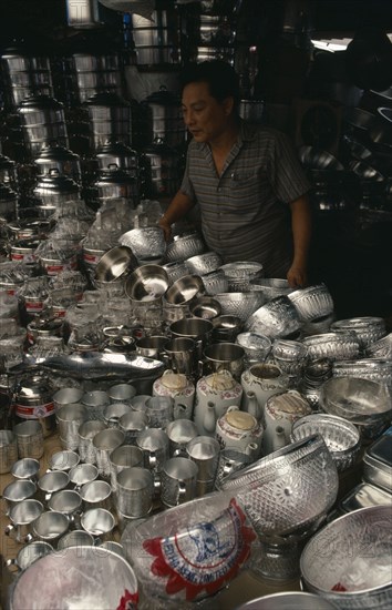 THAILAND, Bangkok, Stall selling chrome / silver kitchen utensils at the weekend market with vendor standing behind.