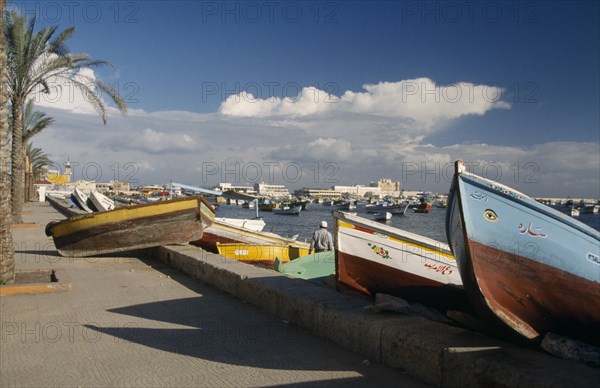 EGYPT, Alexandria, View of fishing boats pulled ashore with view of the harbour and Fort Qaitbey  in the distance.