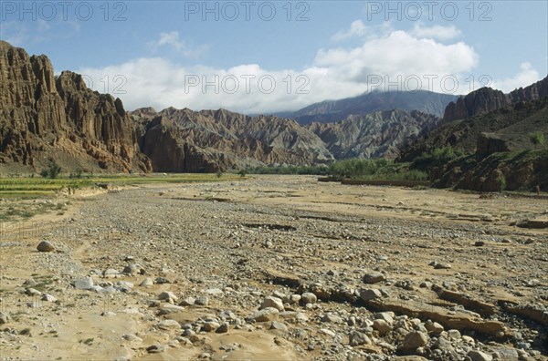 CHINA, Qinghai , Dry gravel bed of seasonal river in canyon surrounded by high altitude cliffs