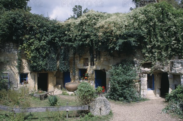 FRANCE, Loire, Les Maisons Trogladytes / La Fosse de Forges. Old style cottages rooved by overhanging trees and ivy.