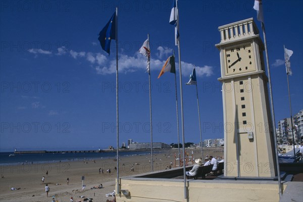 FRANCE, Loire, Les Sables d’Olonne, Twinned with Worthing. Clock tower on the promenade with sandy beach beyond