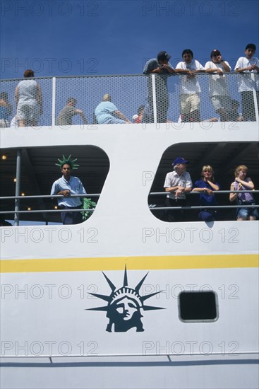 USA, New York, New York City, Circle Line ferry to Liberty Island with passengers leaning over the sides