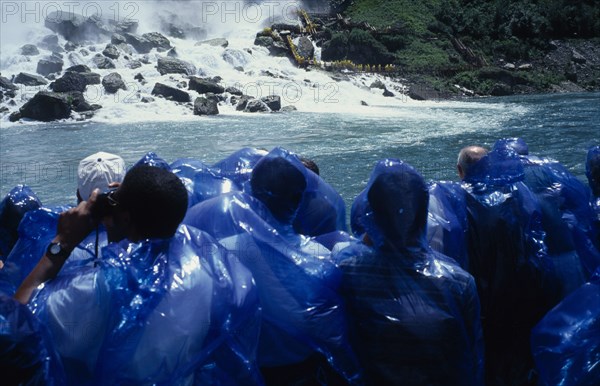 CANADA, Ontario, Niagara Falls, Maid of the Mists tourists in blue waterproofs looking toward American Falls