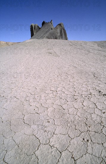 USA, Utah, North Pinto Hills, View over cracked dry earth toward rock formation on the horizon