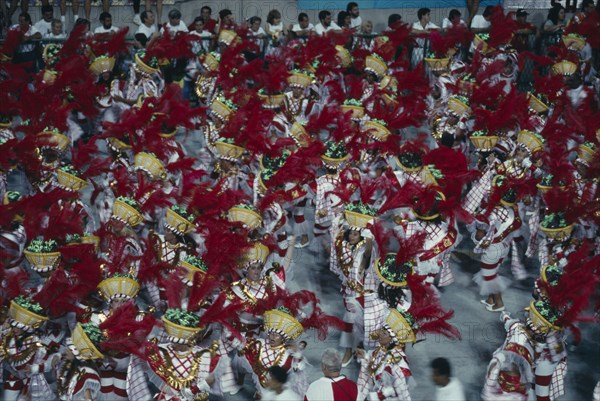 BRAZIL, Rio de Janeiro, Carnival procession of dancers wearing red feathered head dresses
