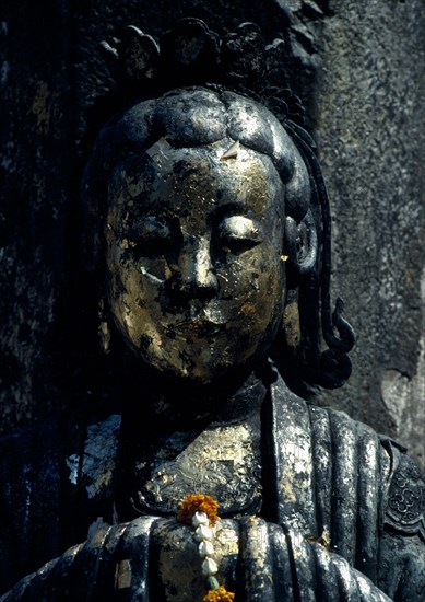 THAILAND, Bangkok, Wat Phra Kaew, Or Royal Palace. Close up detail of golden statue with floral arrangement placed on her clasped hands