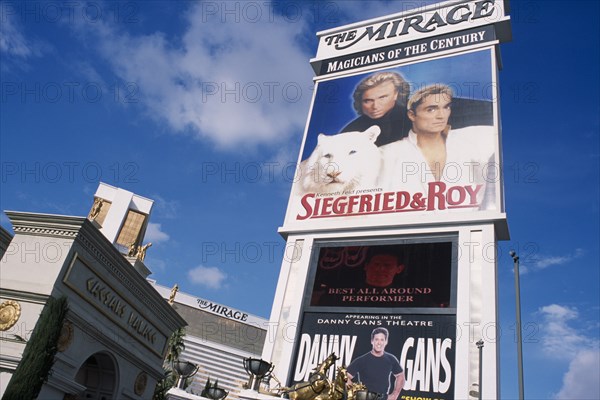 USA, Nevada, Las Vegas, Mirage hotel and casino with signs for Caesar’s Palace with Siegfried & Roy in the foreground