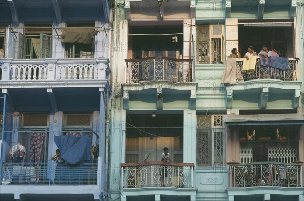 MYANMAR, Yangon, Building detail of balconies with hanging washing and people standing