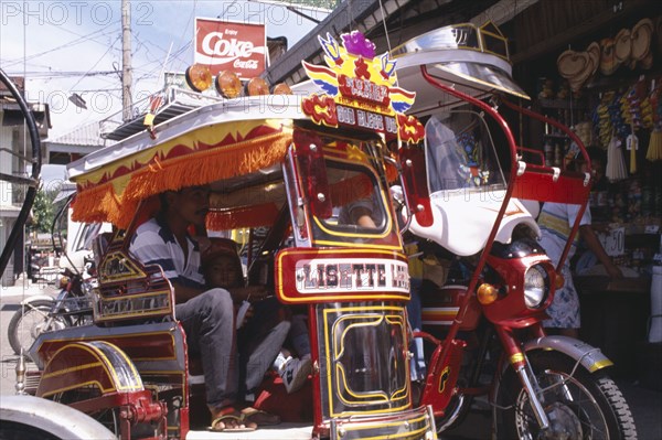 PHILIPPINES, Marinduque Island, Boac, Moriones Festival. Close up of brightly coloured tricycle with pasengers in side cart