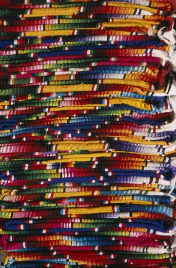 MEXICO, Chiapas, San Cristobal de Las Caras, Close view of layered pile of multicoloured textiles.