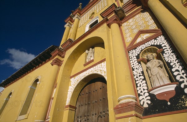 MEXICO, Chiapas, San Cristobal de Las Casas, "Catedral de San Cristobal.  Sixteenth century cathedral painted in brown, white and yellow. Part view of exterior wall with statue set into niche surrounded by plant motif."