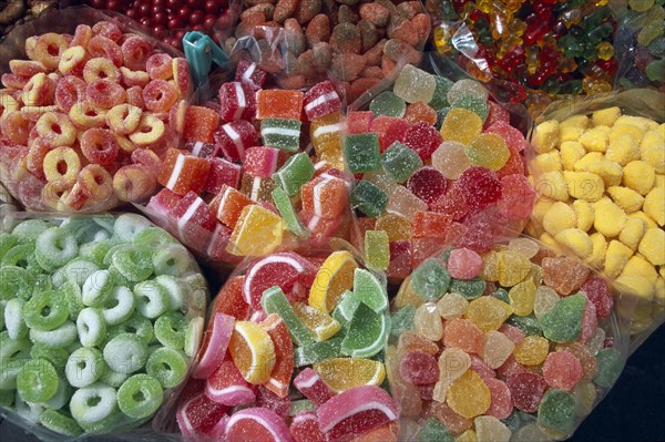 MEXICO, Mexico City, Close view of open topped bags of colourful sweets for sale.