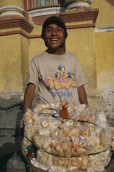 MEXICO, Chiapas, San Cristobal de Las Casas, Street food vendor with basket piled with bags of popcorn and other snacks.