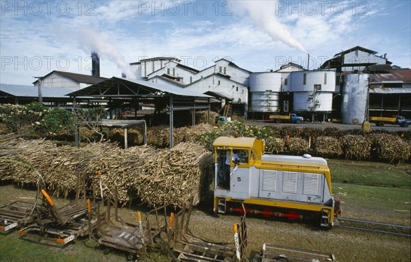 PACIFIC ISLANDS, Melanesia, Fiji, "Viti Levu, south. Sugar cane refinery with train loaded with cut cane in the foreground."