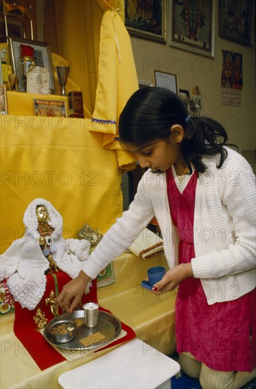 ENGLAND, Religion, Hindu, Young girl kneeling on floor preparing shrine for prayer.