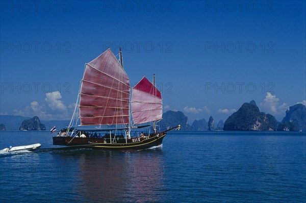 THAILAND,  , Phuket, Tourist excursion on Chinese Junk with pink sails reflected in deep blue water.