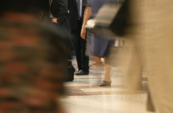 BUSINESS, Commuters, Cropped shot of business man in suit standing still surrounded by crowds in blurred movement.