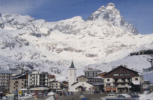 ITALY, Valle d’Aosta, Breuil Cervinia, "Ski resort town with church, hotel and petrol pumps with snow covered peak of the Matterhorn behind."