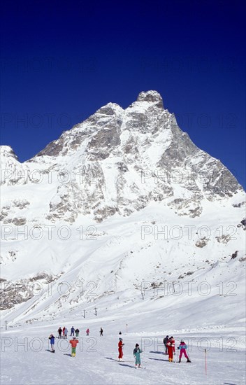 ITALY, Valle d’Aosta, Breuil Cervina, Skiers on slopes at the foot of the Matterhorn.