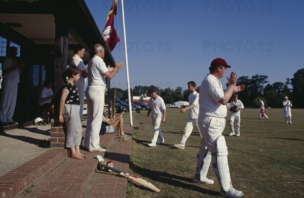 20027336 SPORT Ball Cricket Village cricket members applauding Team as they come off the pitch.