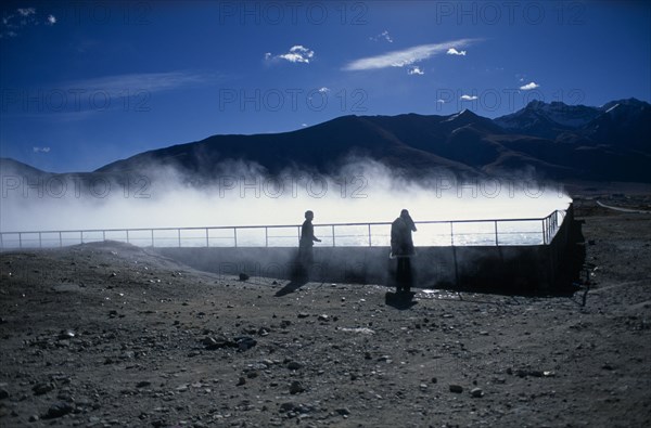 CHINA, Tibet, Lhasa, Yangpachen geothermal powerstation with two women stood beside a pool of steaming water.