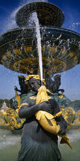 FRANCE, Ile de France, Paris, Place de La Concorde.  Detail of fountain with sculpted female figure holding a golden fish spouting water.