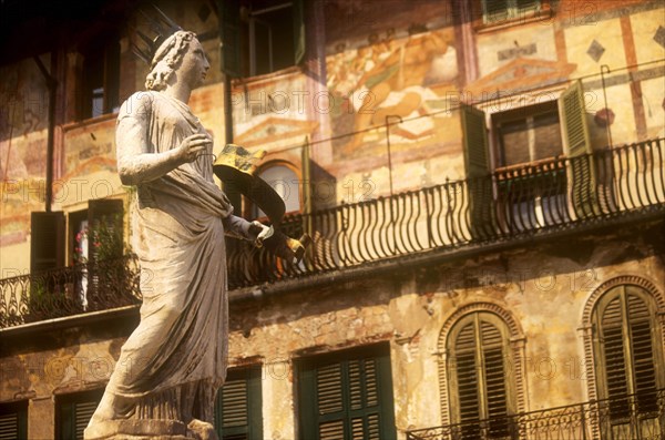 ITALY, Veneto, Verona, "Piazza della Erbe. Detail of the Fountain of Madonna, statue of female figure in crown in front of building with painted facade, green window shutters and balcony."