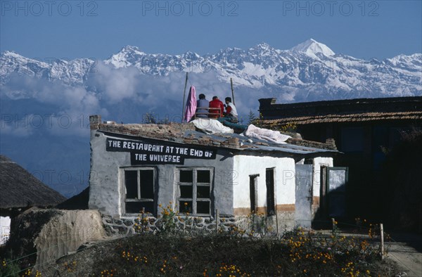 20027664 NEPAL  Himalayas The Restaurant At The End Of The Universe with three men sitting on the roof surrounded by snow capped mountain peaks