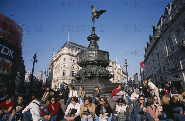 ENGLAND, London, Piccadilly Circus with mixed young crowd congregated around base of Alfred Gilberts statue of Eros