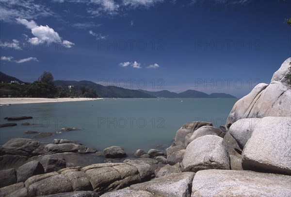 MALAYSIA, Penang, Batu Ferringhi, View over rocks and bay of turquoise water towards quiet sandy beach.