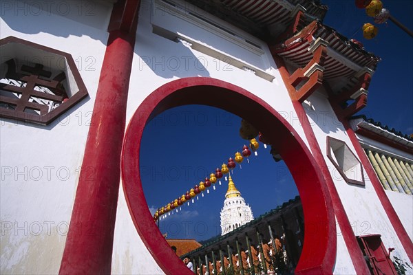 MALAYSIA, Penang, Kek Lok Si Temple, "Ban Po, the Pagoda of a Thousand Buddhas and string of red and yellow coloured Chinese lanterns framed by circular opening in red and white painted wall."