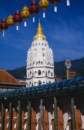 MALAYSIA, Penang, Kek Lok Si Temple, "Covered colonnade with line of standing Buddha figures and Ban Po, the Pagoda of a Thousand Buddhas behind.  String of red and yellow Chinese lanterns above. "
