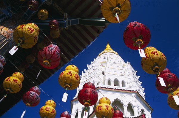 MALAYSIA, Penang, Kek Lok Si Temple, "Ban Po, the Pagoda of a Thousand Buddhas. Tiered top with strings of red and yellow Chinese New Year lanterns hanging from overhanging roof in foreground. "