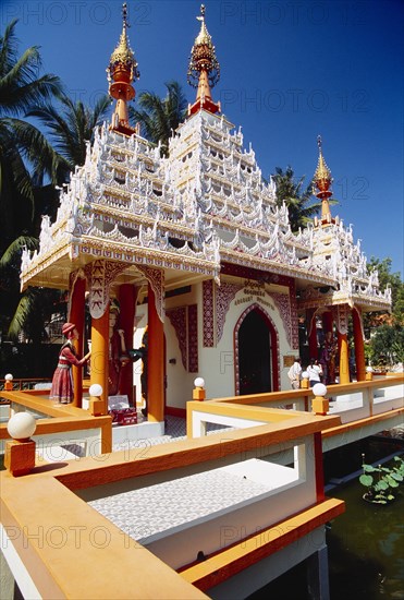 MALAYSIA, Penang, Georgetown, Dharmikarama Burmese Temple.  Exterior with ornate carved roof and statues.  Visitors outside arched entrance.