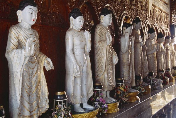 MALAYSIA, Penang, Georgetown, Dharmikarama Burmese Temple.  Interior with large standing Buddha figure with raised hand in gold painted robe and ornate carved gold panel behind.